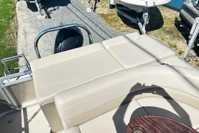 Slide: The Image of 2016 Avalon LSV Tri Toon boat with beige seating and motor, parked on gravel. - 9