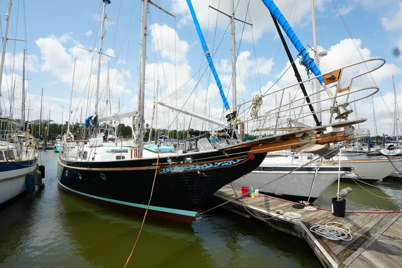 The Image of 1982 Vagabond 47 sailboat docked at marina, featuring blue sails and decorative hull design. - 0