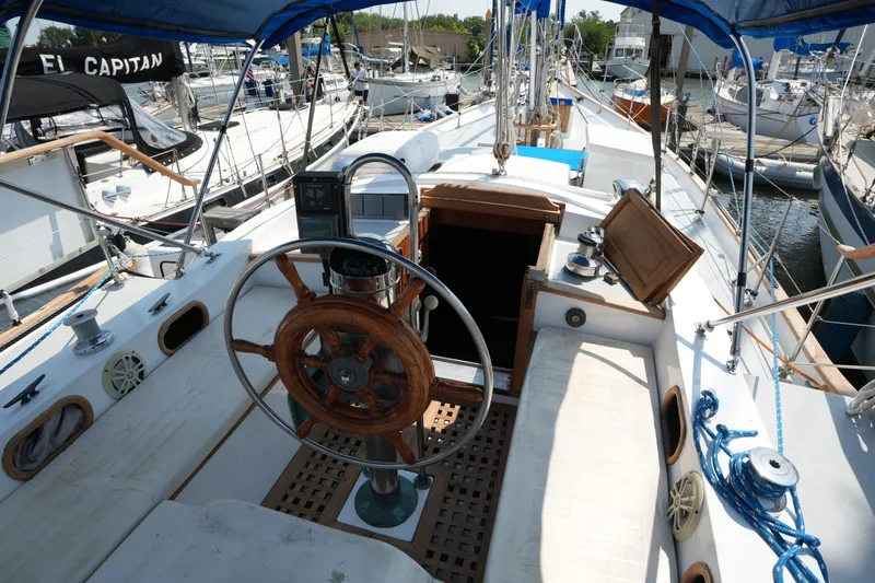 Slide: The Image of Cockpit of 1982 Vagabond 47 sailboat with wooden steering wheel and nautical equipment. - 16