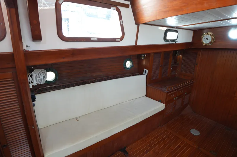Slide: The Image of Interior of 1982 Vagabond 47 sailboat with wooden paneling and white cushioned seating. - 21