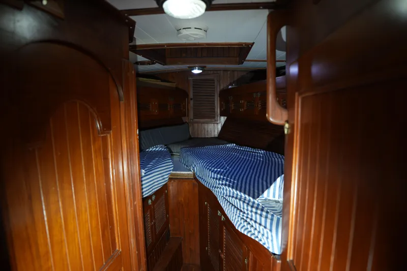 Slide: The Image of Cozy wooden cabin interior of 1982 Vagabond 47 sailboat with striped bedding. - 22