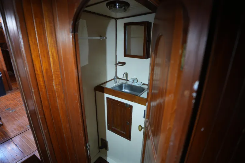 Slide: The Image of Compact wooden bathroom interior on a 1982 Vagabond 47 sailboat, featuring a sink and mirror. - 24