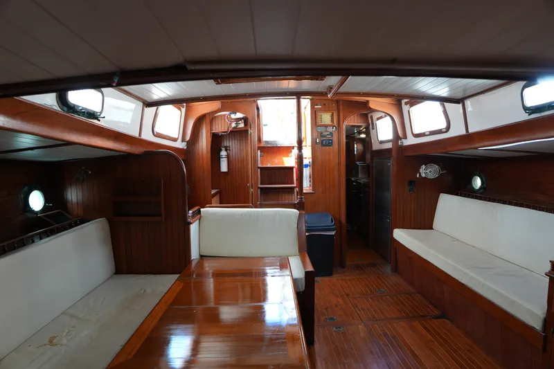 Slide: The Image of Interior of 1982 Vagabond 47 sailboat with wooden furnishings and white seating. - 25