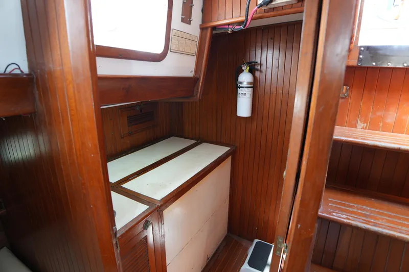 Slide: The Image of Wood-paneled interior of 1982 Vagabond 47 sailboat with storage and fire extinguisher. - 28