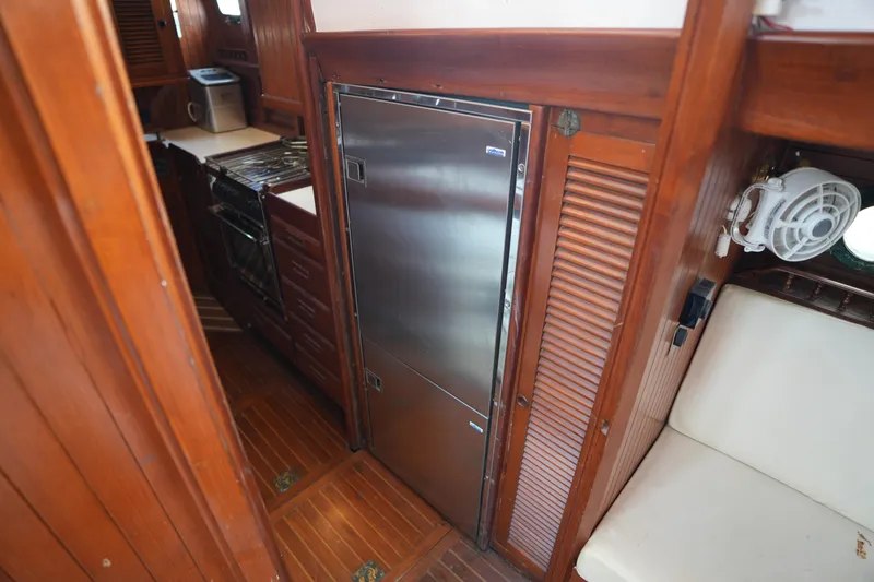 Slide: The Image of Interior of 1982 Vagabond 47 yacht featuring a compact kitchen with stainless steel appliances. - 30