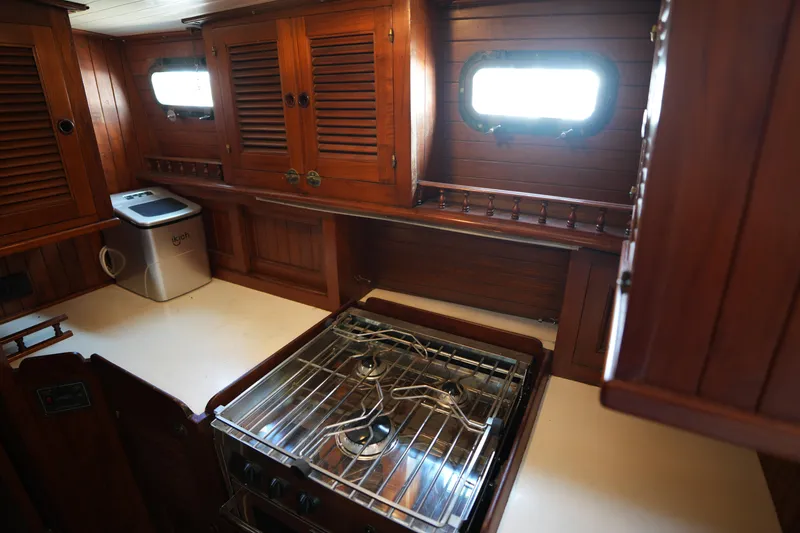 Slide: The Image of Vintage 1982 Vagabond 47 yacht kitchen with wooden cabinets and gas stove. - 32