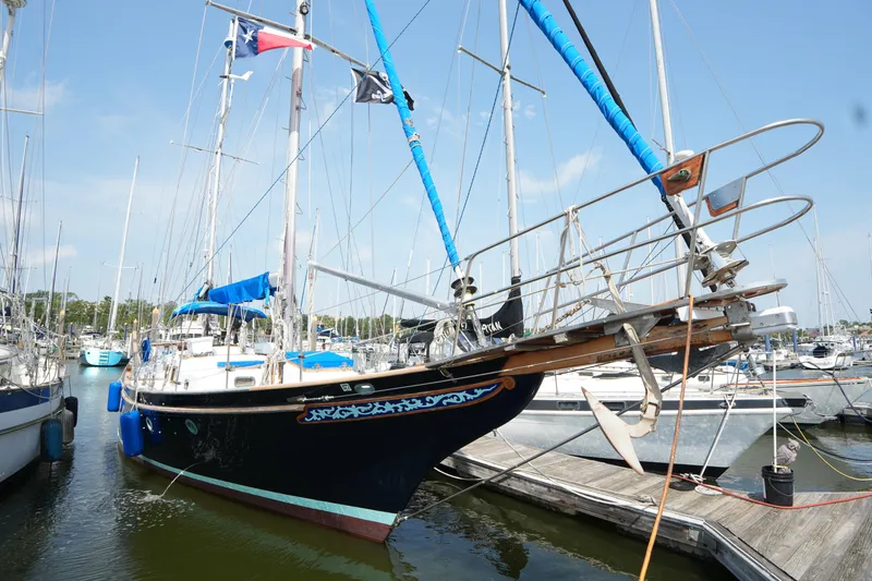 Slide: The Image of Sailboat docked in marina, Vagabond 47 model, 1982, with blue accents and flags. - 7