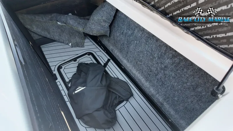Slide: The Image of A storage compartment inside a 2013 Nautique G23 boat with gray carpeted flooring. - 26