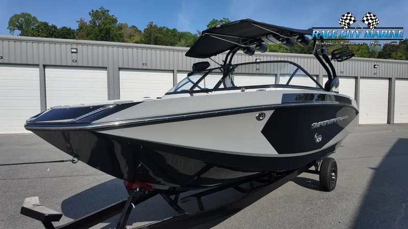 Slide: The Image of A black and white 2013 Nautique G23 boat on a trailer in front of garages. - 6