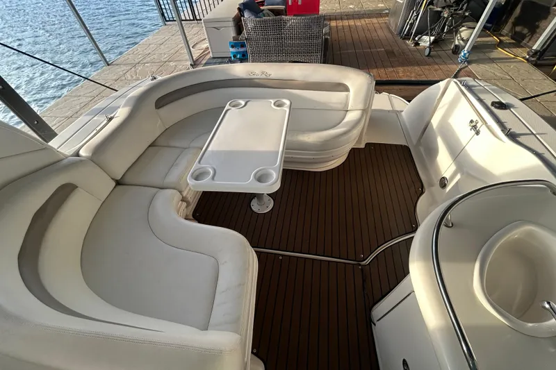 Slide: The Image of 2003 Sea Ray 340 Sundancer boat interior with white seating and table on wooden deck. - 10