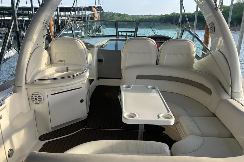 Slide: The Image of 2003 Sea Ray 340 Sundancer interior with seating, table, and sink, docked by the water. - 2