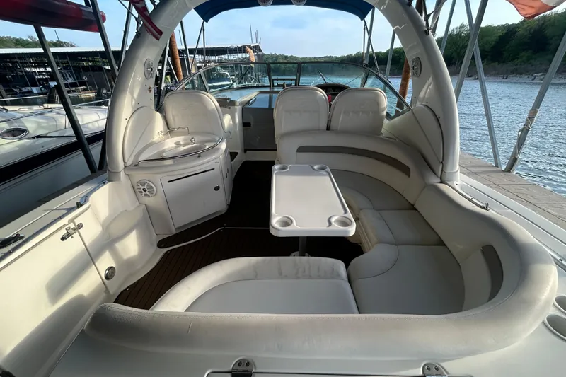 Slide: The Image of 2003 Sea Ray 340 Sundancer boat interior with seating and table, docked by the water. - 9