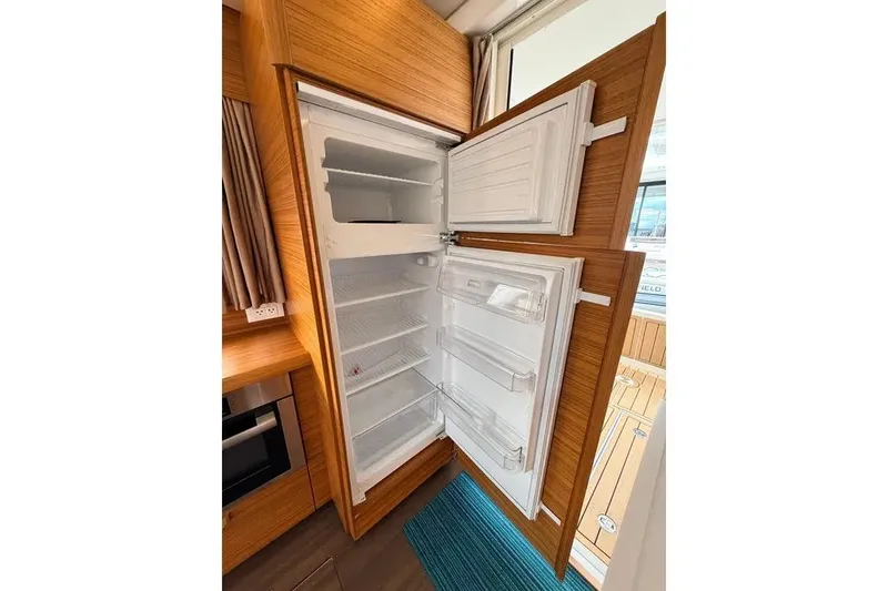 Slide: The Image of Open refrigerator inside 2024 Greenline 39 yacht, showcasing spacious interior and wooden paneling. - 11