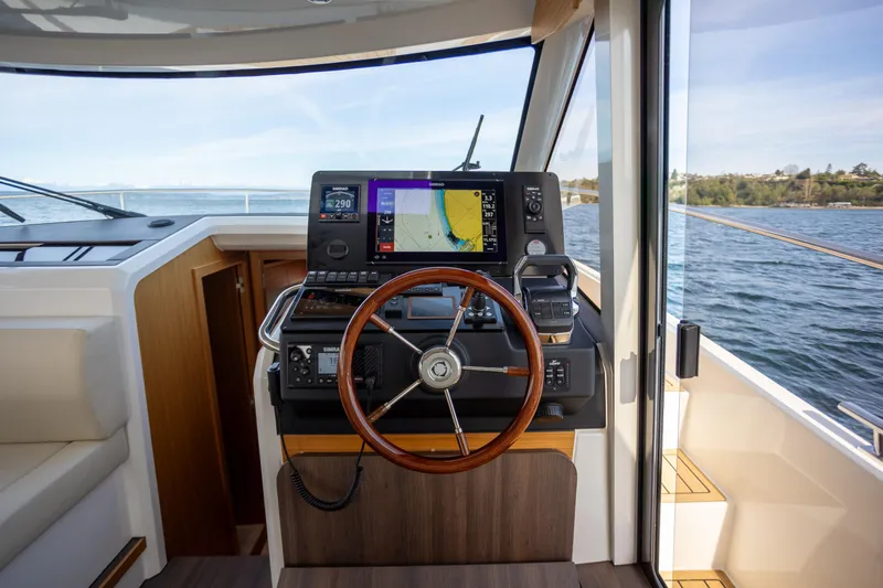 Slide: The Image of 2024 Greenline 39 yacht helm with navigation display and wooden steering wheel. - 18