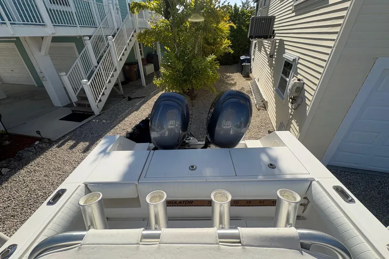 Slide: The Image of 2006 Regulator 24 Classic boat with dual engines, parked near a house. - 10