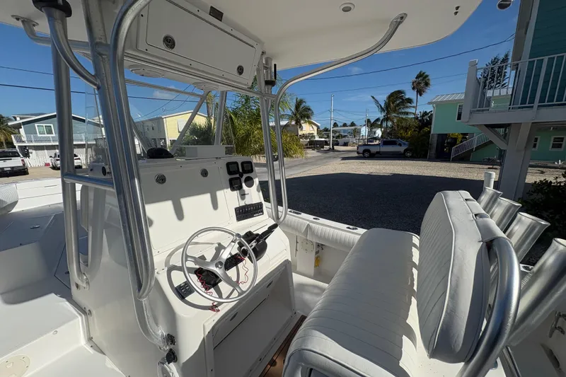 Slide: The Image of 2006 Regulator 24 Classic boat interior with steering wheel and seating, parked near coastal homes. - 15