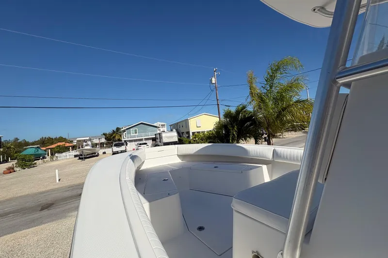 Slide: The Image of 2006 Regulator 24 Classic boat with white seating, parked near coastal homes. - 16
