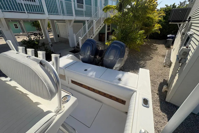 Slide: The Image of 2006 Regulator 24 Classic boat with dual engines, parked near a coastal home. - 9