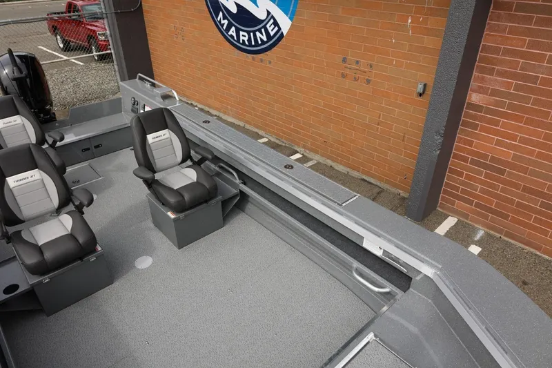 Slide: The Image of 2026 Thunder Jet 209 Rush OT boat interior with seating, parked near a brick wall. - 19