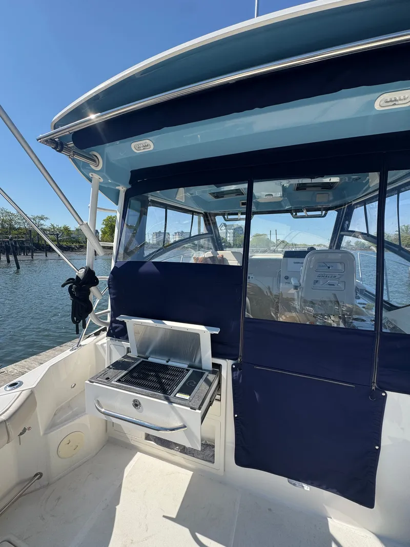 Slide: The Image of 2024 Boston Whaler 325 Conquest boat door open by water. - 13