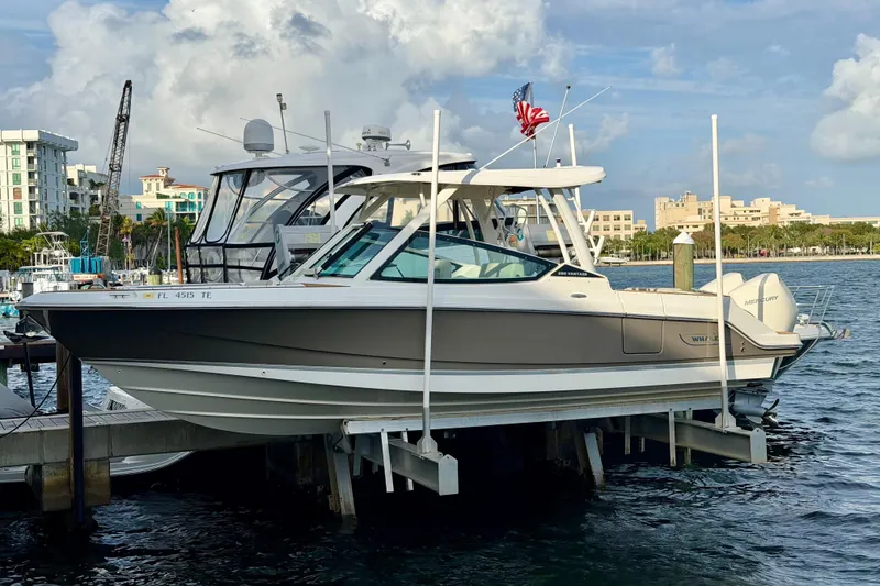 Slide: The Image of 2022 Boston Whaler 280 Vantage boat docked at marina with cityscape background. - 3