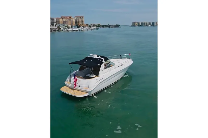 The Image of 2002 Sea Ray 380 Sundancer yacht cruising in clear blue waters near a coastal city. - 0