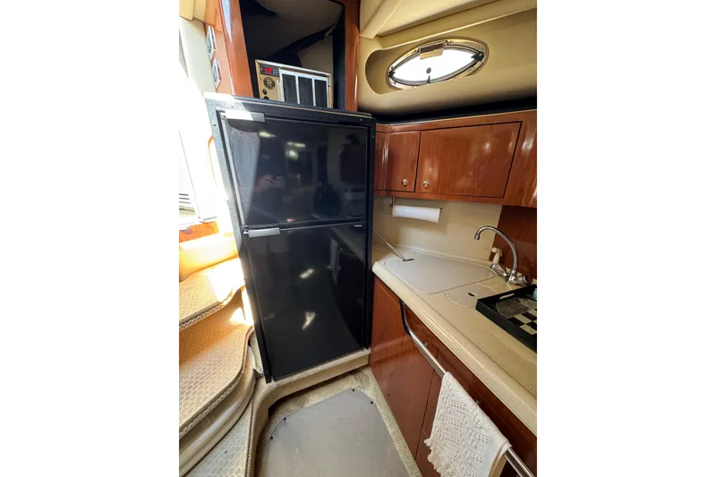 Slide: The Image of 2002 Sea Ray 380 Sundancer yacht kitchen with fridge, sink, and wooden cabinets. - 30
