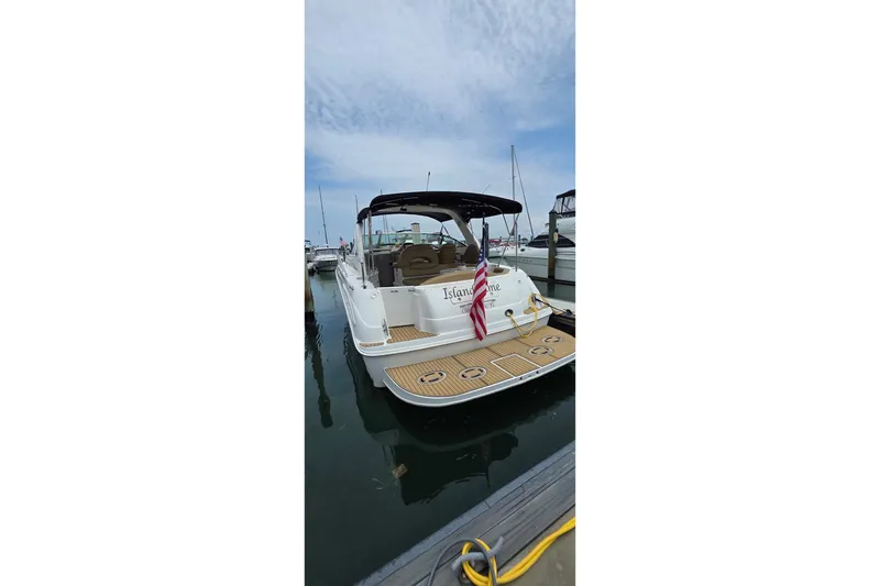 Slide: The Image of 2002 Sea Ray 380 Sundancer docked at marina, rear view with American flag. - 49