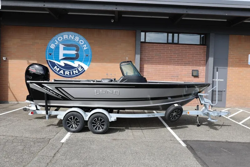 The Image of 2026 Lund 1875 Impact XS Sport boat on trailer at Bjornson Marine dealership. - 1