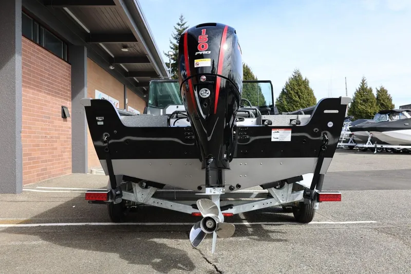Slide: The Image of 2026 Lund 1875 Impact XS Sport boat with powerful outboard motor, parked outdoors. - 12