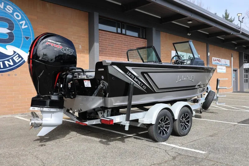 Slide: The Image of 2026 Lund 1875 Impact XS Sport boat on trailer, parked outside dealership. - 14