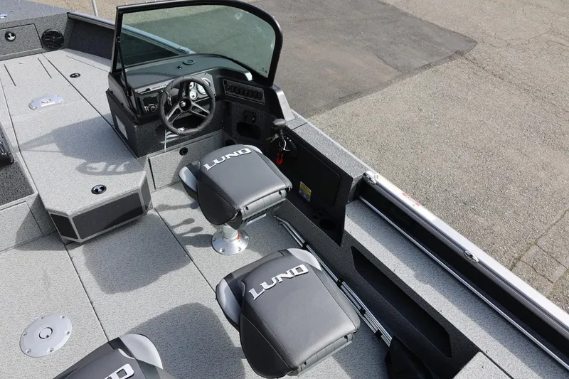 Slide: The Image of 2026 Lund 1875 Impact XS Sport boat interior with steering console and branded seating. - 21