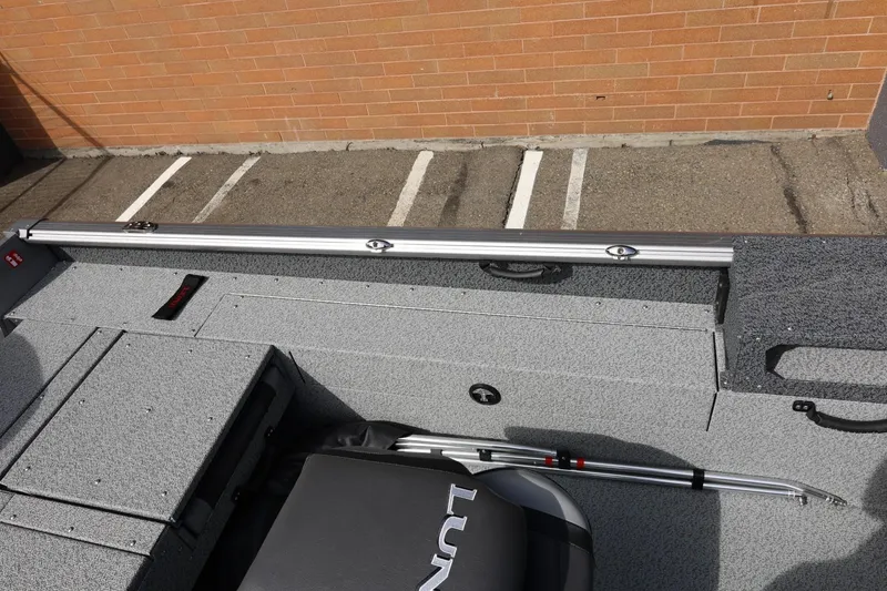 Slide: The Image of 2026 Lund 1875 Impact XS Sport boat interior with gray flooring and storage compartments. - 28