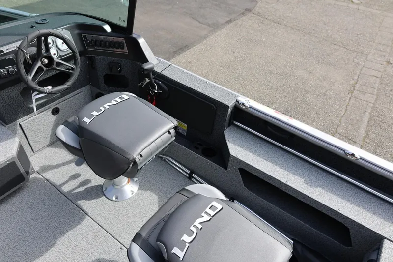 Slide: The Image of 2026 Lund 1875 Impact XS Sport boat interior with steering wheel and branded seats. - 33