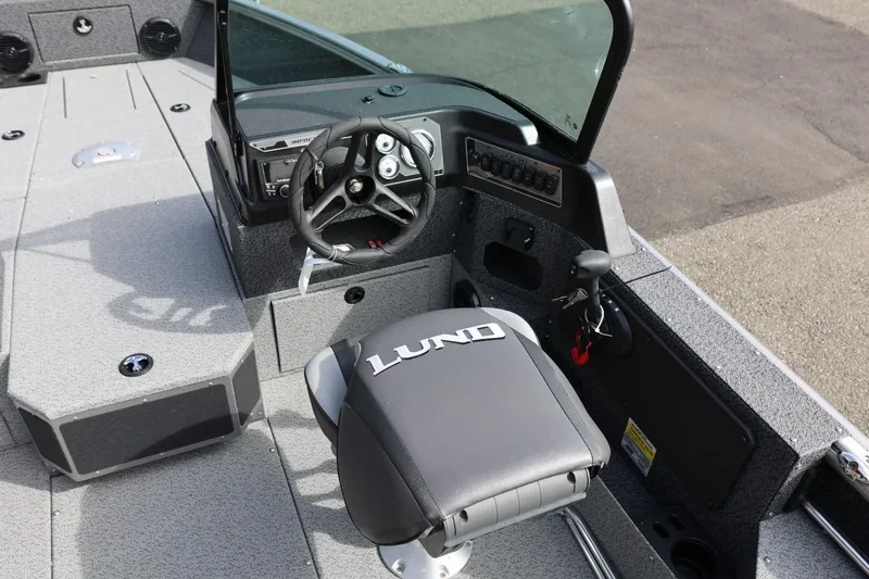 Slide: The Image of 2026 Lund 1875 Impact XS Sport boat interior with steering wheel and branded seat. - 34