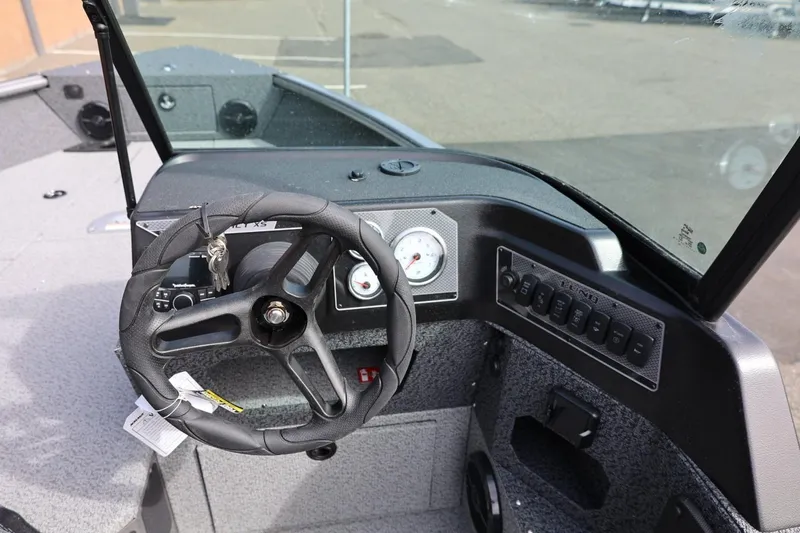 Slide: The Image of 2026 Lund 1875 Impact XS Sport boat dashboard with steering wheel and control panel. - 36