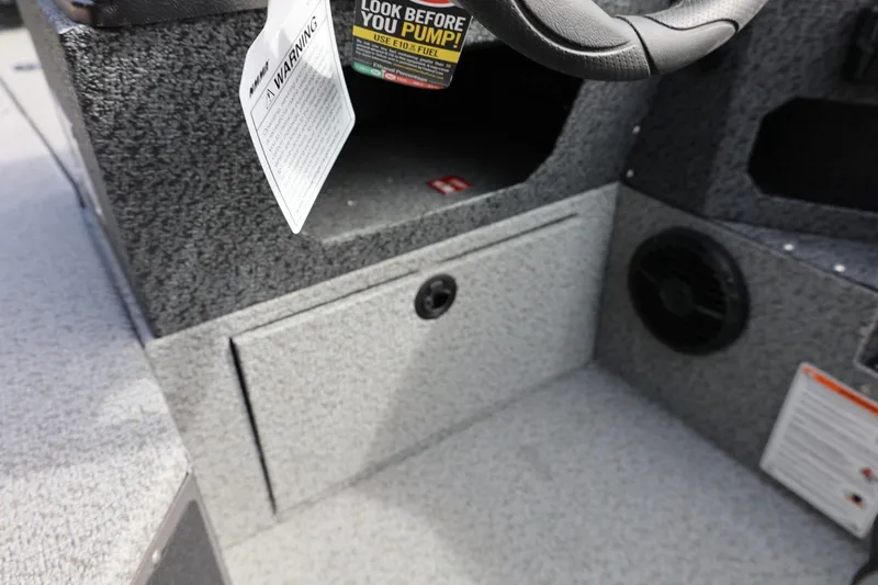 Slide: The Image of 2026 Lund 1875 Impact XS Sport boat interior with steering wheel and warning labels. - 37