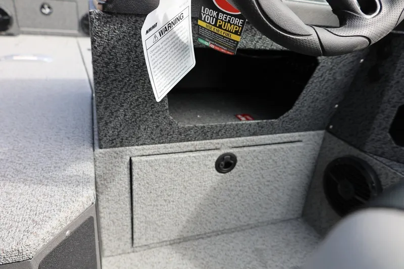 Slide: The Image of Interior of 2026 Lund 1875 Impact XS Sport boat, featuring steering wheel and storage compartment. - 38