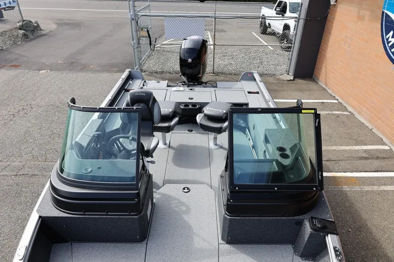 Slide: The Image of 2026 Lund 1875 Impact XS Sport boat with dual consoles and seating, parked outdoors. - 51