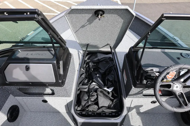 Slide: The Image of 2026 Lund 1875 Impact XS Sport boat interior with open storage compartment and steering wheel. - 41