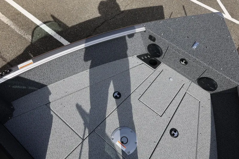 Slide: The Image of 2026 Lund 1875 Impact XS Sport boat interior with gray textured flooring and storage compartments. - 46