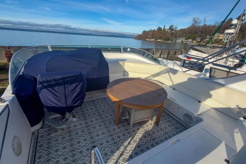 Slide: The Image of 2002 Bayliner 3988 Command Bridge Motoryacht deck with seating and table, overlooking serene waters. - 8