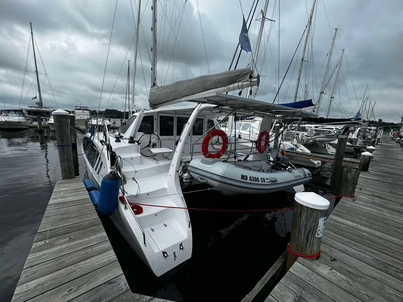 The Image of 2023 Seawind 1160 Lite catamaran docked at a marina with lifebuoys and dinghy. - 1