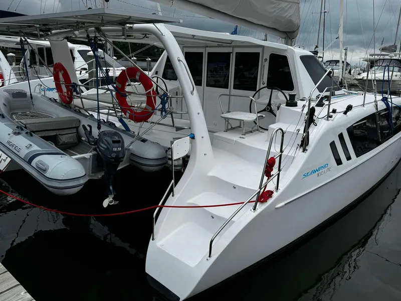 Slide: The Image of 2023 Seawind 1160 Lite catamaran docked at marina with lifebuoys and dinghy. - 5
