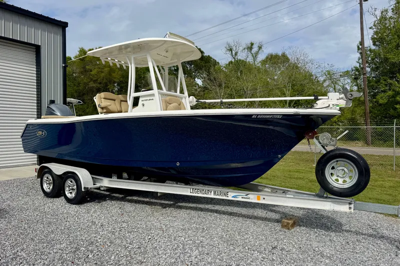 The Image of 2016 Sea Hunt Ultra 234 boat on trailer, parked outdoors near a metal building. - 1