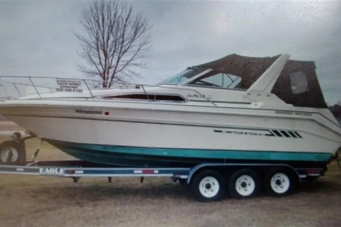 Slide: The Image of 1993 Sea Ray 290 Sundancer boat on trailer, parked outdoors, with overcast sky. - 11