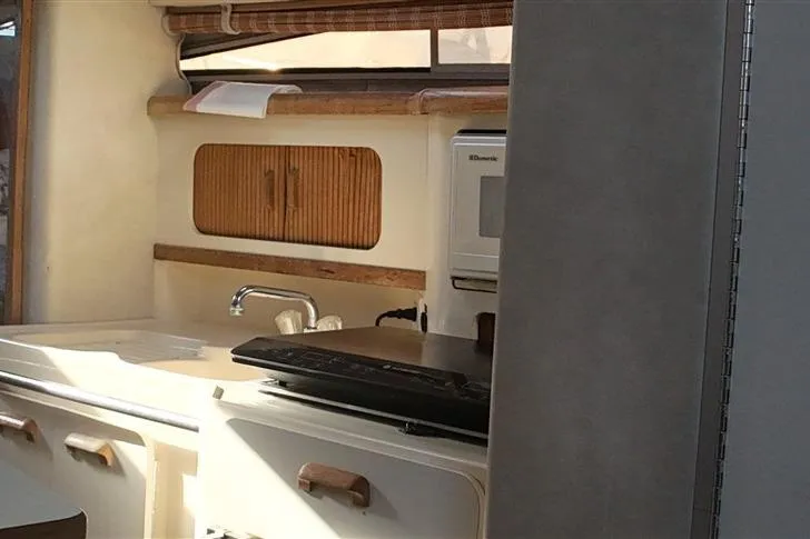 Slide: The Image of Interior of a 1993 Sea Ray 290 Sundancer boat, featuring a compact kitchen area. - 12
