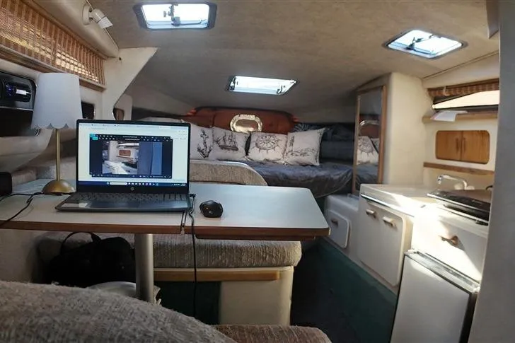 Slide: The Image of Interior of a 1993 Sea Ray 290 Sundancer with laptop, table, and cozy seating. - 14
