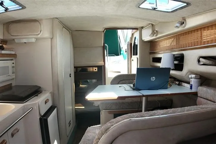 Slide: The Image of Interior of a 1993 Sea Ray 290 Sundancer boat with a cozy dining area and kitchenette. - 16