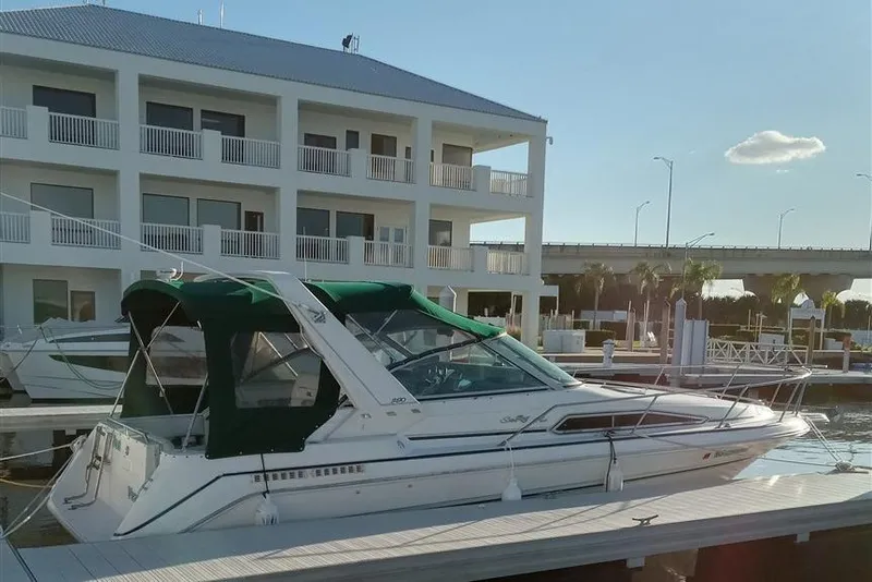 Slide: The Image of 1993 Sea Ray 290 Sundancer docked at marina with modern building backdrop. - 3